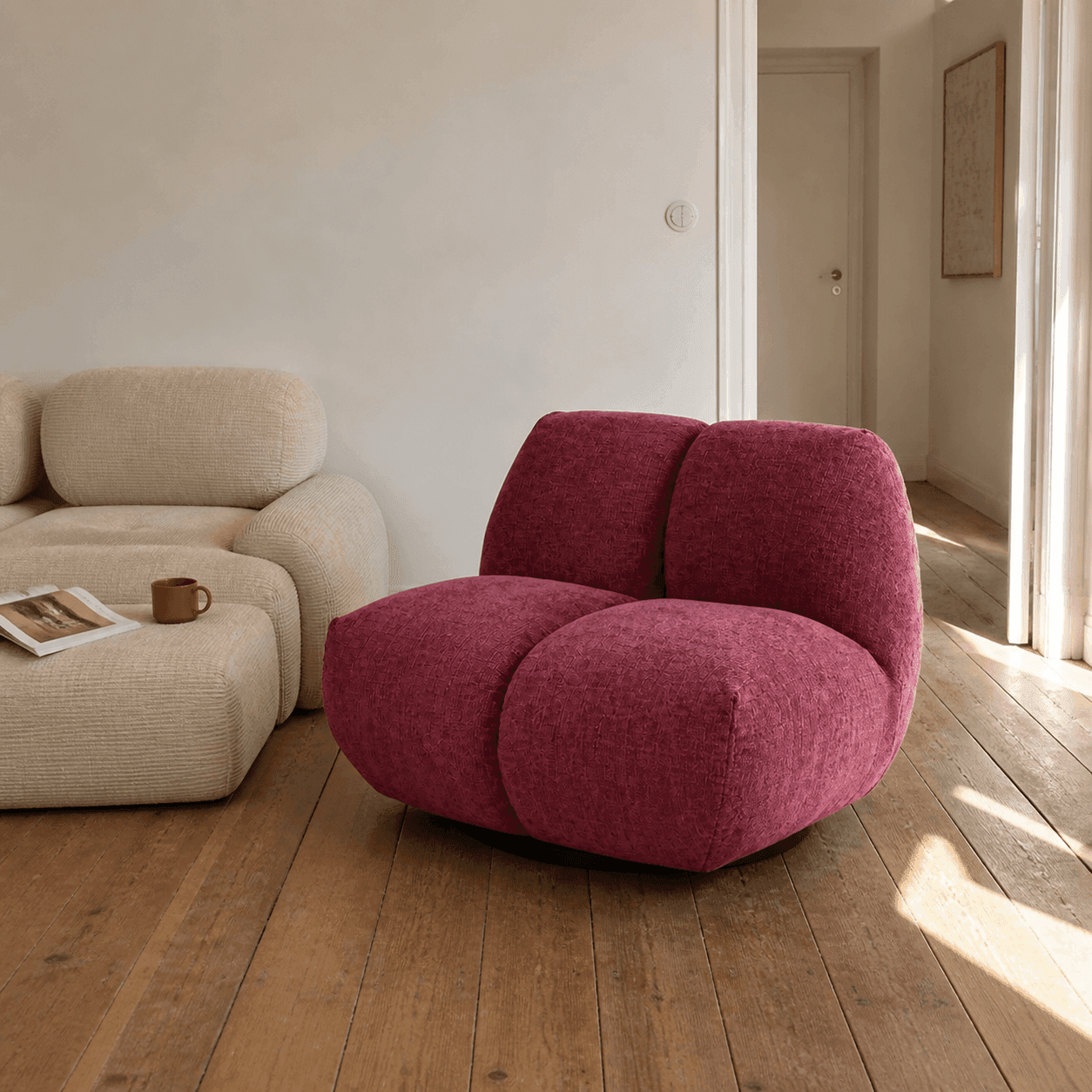 Fauteuil rose compact associé à un canapé beige dans un salon lumineux